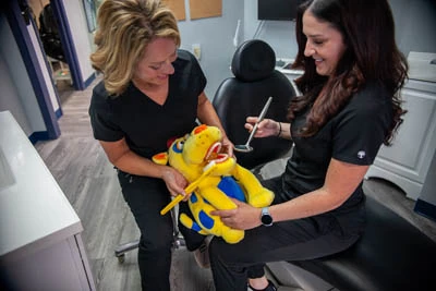 children's dentists at All Smiles Dental showing how to brush teeth using a stuffed animal