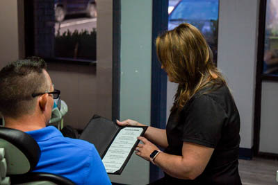 patient being shown a list of comfort services offered at All Smiles Dental